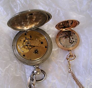 two old watches with backs opened to show mechanism