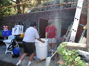 two men moving a 50 gallon drum of wine crush into the fallout shelter in Saratoga California