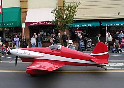 red stunt plane driving down the road in a parade