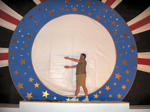 man standing in middle of a blue plate on stage, almost naked
