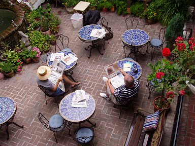 italian courtyard with blue mosaic tiles and two people reading the newspaper