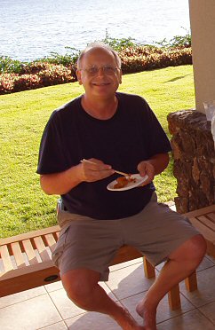 man sitting with a plate of food and a big grin