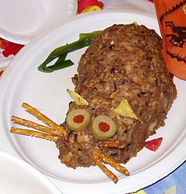 meat loaf in the shape of a rat with olive eyes and pretzel whiskers