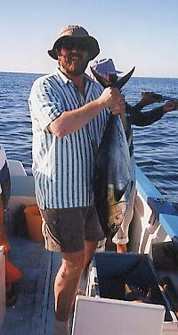 Jim holding up a 40 pound tuna in a small skiff