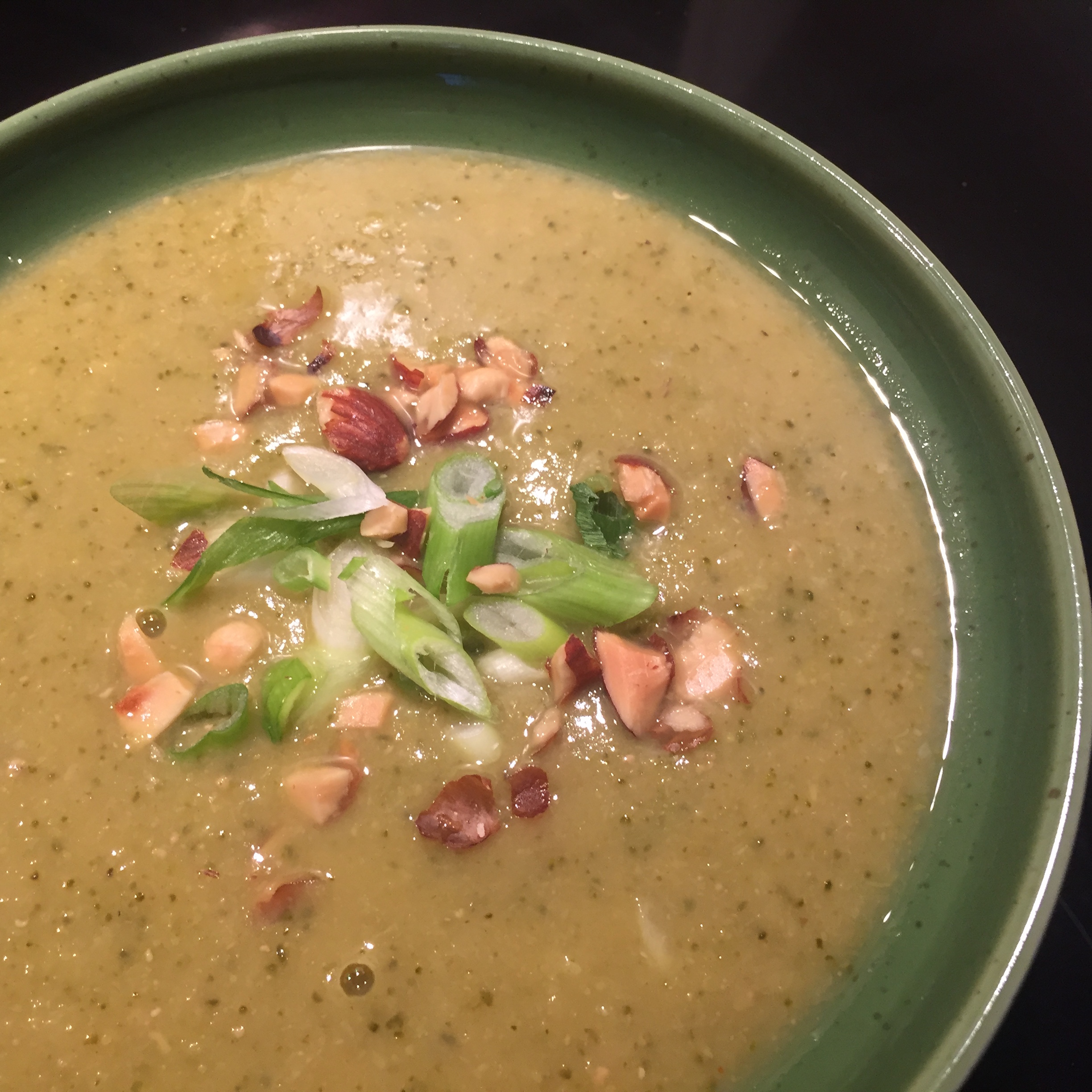 brown soup with cut scallions and almonds on top