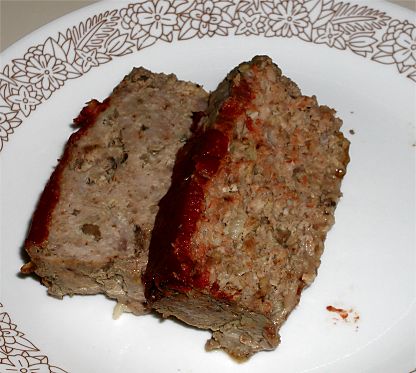 two slices of meatloaf on a white and brown correll plate