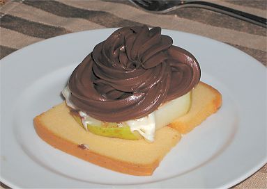 dessert on a plate with a tower of sponge cake, pear, brie, and chocolate mousse or ganache